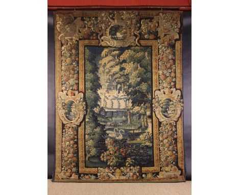 A 17th Century Verdure Tapestry depicting a landscape with swans in river framed by a broad borer of floral bands incorporati