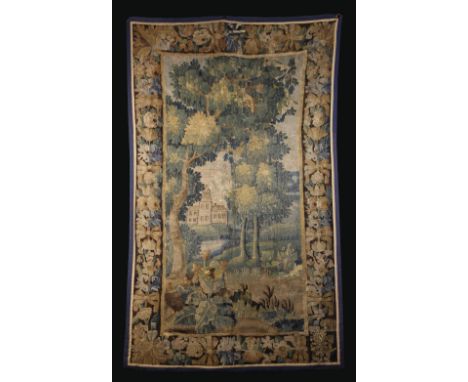 A Late 17th Century Verdure Tapestry Fragment depicting a house with tower in landscape framed by a border of flowers and fol