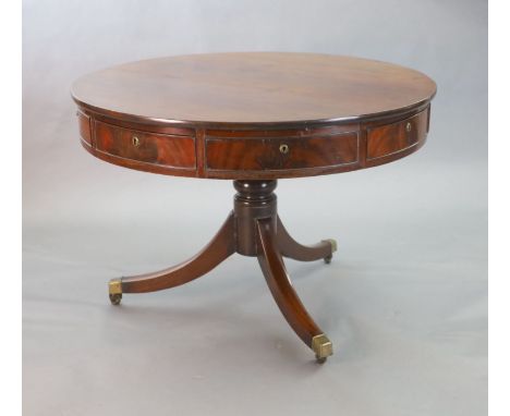 A Regency mahogany drum top library table, fitted four frieze drawers on ring turned stem and downswept legs, fitted brass ca