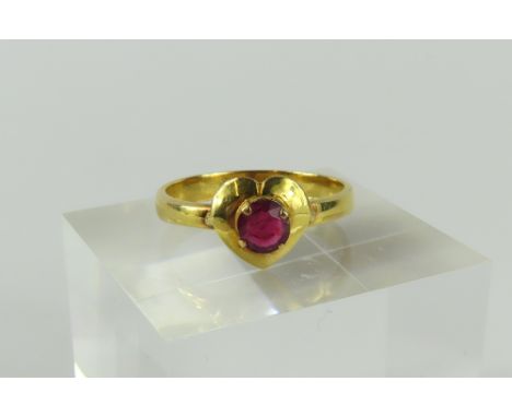 A ruby dress ring, the single round stone in a four claw setting on a heart shaped head, acid tests as approximately 18-22ct 