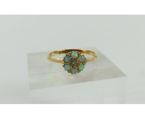 A white opal and diamond cluster ring, the small diamond in a star shaped setting with a row of six opals around, marked '18c