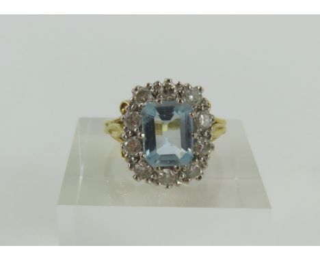 An 18ct gold aquamarine and diamond cluster ring, the rectangular step cut aquamarine in claw setting and with a row of diamo