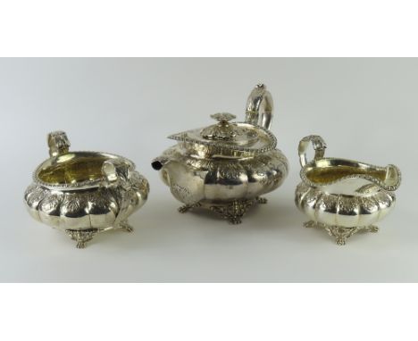 A Georgian silver tea set, comprising a teapot, milk jug and sugar bowl. The items are decorated elaborately, with round bodi