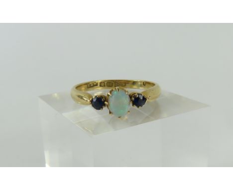 An 18ct gold opal and sapphire three stone ring, the oval cabochon cut opal in claw setting with a single sapphire to each si