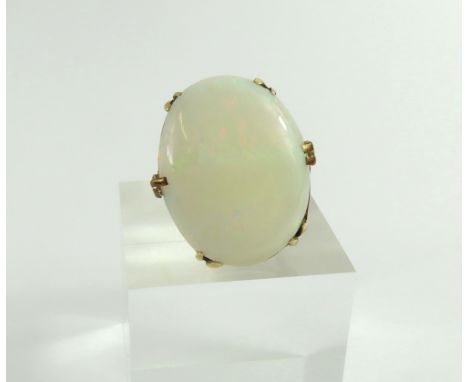 A large white opal dress ring, the flat oval cabochon cut opal set in six pairs of double claws, finger size O, acid tests as