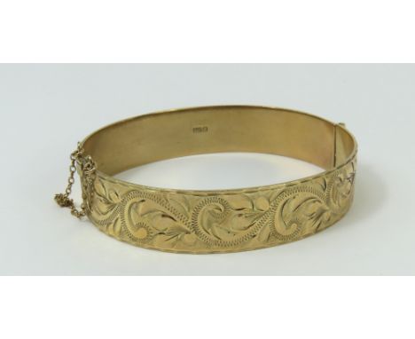 A 9ct gold hinged bangle, half decorated with chased engraving, internal diameter 6cm, 24.57g gross