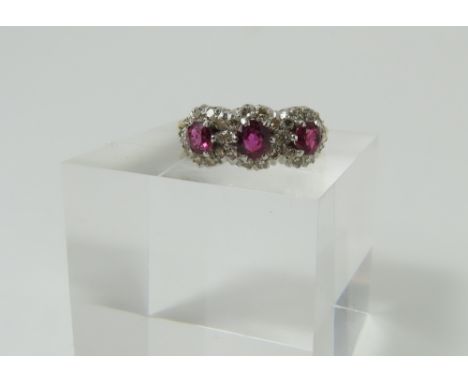 A ruby and diamond triple cluster ring, the three round rubies with a row of diamonds around each, with lightly decorated sho