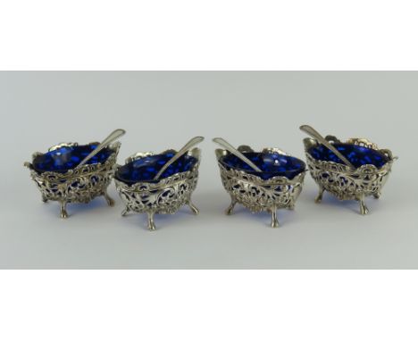 Four silver salt pots with glass inserts and Victorian spoons. The pots similarly designed, with cut floral patterns that def