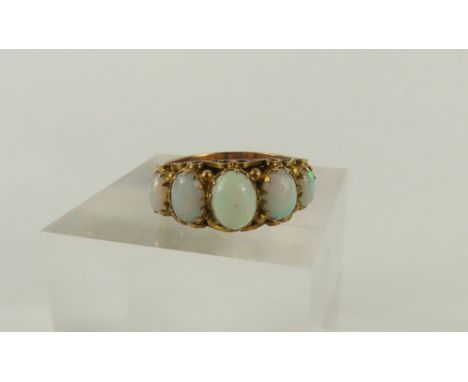 A 9ct gold late 19th or 20th century five stone white opal ring, the oval cabochon cut stones graduated, in decorative claw s