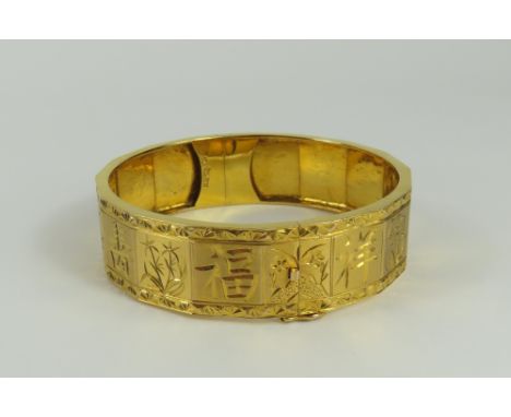 A hinged gold bangle, decorated with Chinese character marks and floral motifs, internal diameter 5.9cm, marked '18k', 32.48g