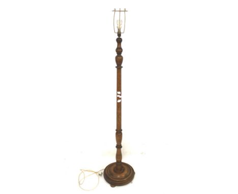 A 20th century oak standard lamp. The turned stand mounted on a circular base with bun feet, H151cm