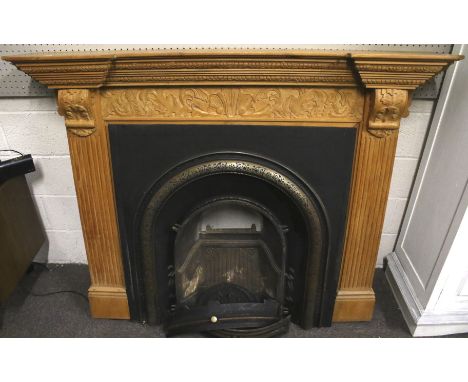 A cast metal fire place and carved pine surround. The fire place with a grate and moulded details, H123.5cm x W160cm x D31cm