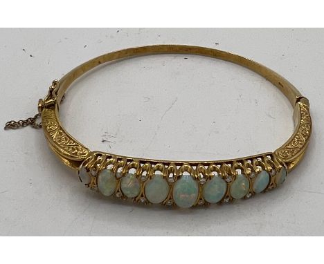 An 18 carat gold hinged bangle set with 9 opals and 16 diamonds. Total weight 19.7gm. 