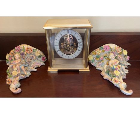 A modern gilt cased mantle clock together with two continental porcelain wall brackets with putti and flowers, 19cm h. 