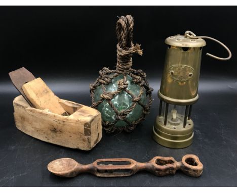 A glass ball fishing weight encased in rope, a brass paraffin miners lamp by Hockley, a wooden carved Welsh love spoon and a 