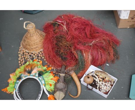 A mixed lot to include an Egrowi Pagwi grass skirt, a nut shell wind chime, a fancy dress feather head dress, a stuffed piran