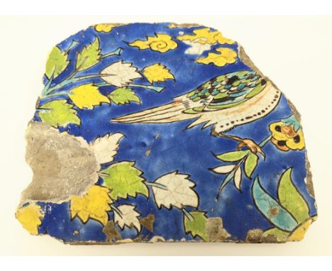 A 17th century Persian Safavid cuerda seca pottery tile depicting a bird on a blue background, 23cm x 20cm