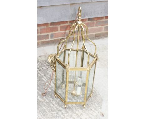 A hexagonal brass framed hall lantern inset bevelled glass panels, 30" high, and a brass three-light table lamp with red and 