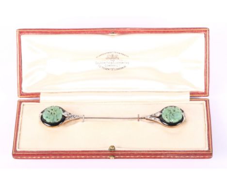 An Art Deco 15ct gold and platinum cloak pin, diamond set with two carved and pierced jade and onyx roundels, in fitted case
