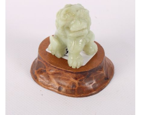 A Chinese carved jade temple lion, 2" high, on hardwood base