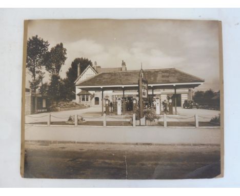 A large photograph of a garage forecourt, with a row of five petrol pumps with Cleveland, Power, Shell and Esso globes.
