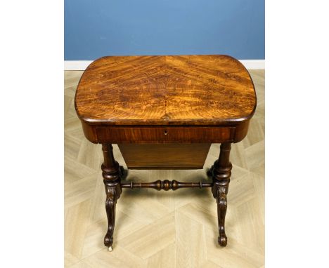 A Victorian walnut work table with a fitted frieze drawer and a pull out basket below, raised upon turned end supports with c
