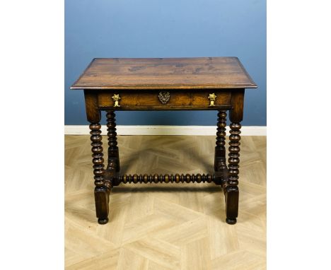 A 17th century style solid oak side table, with a plank top and frieze drawer with split fishtail brass handles, raised upon 