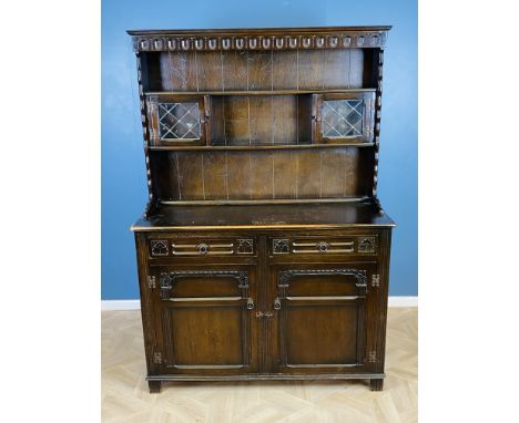 An oak priory style dresser and rack, with leaded light doors to the rack, above two drawers and a pair of cupboard doors bel