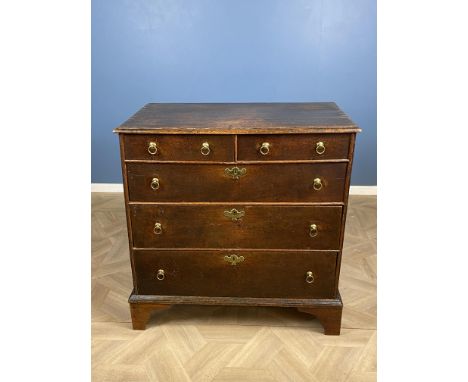 An early 18th century oak chest of two short over three long drawers, with single D-mouldings and brass ring handles, raised 