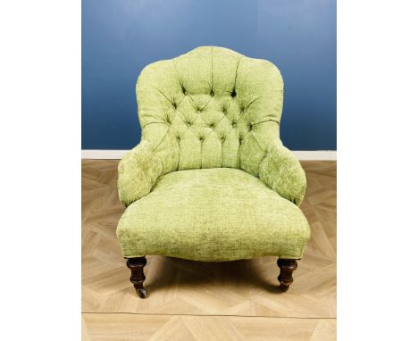 A Victorian stained walnut upholstered button back easy chair, with a serpentine shaped seat and raised upon turned front leg