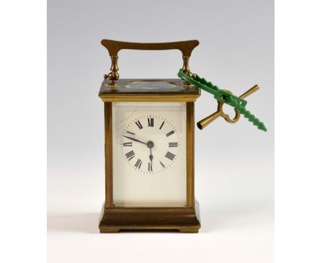 Brass carriage clock with black Roman numerals and white enamel dial, marked for Harrods, London, four glass sides, 11cm high