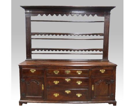 18th century oak dresser base with three central graduated drawers flanked by drawers and panelled cupboards on bracket base,