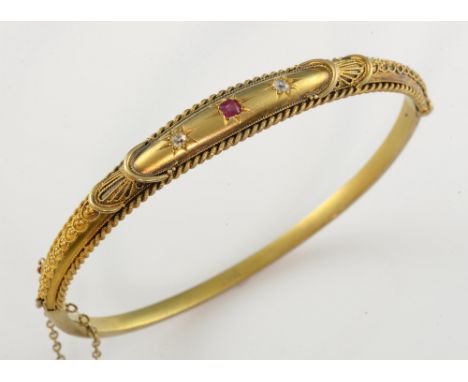 Victorian bloomed gold hinged bangle, set with a ruby and two diamonds, within a rope work decorated mount, 15 ct gold, stamp