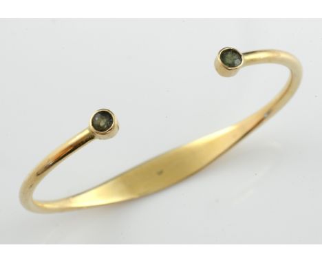 Gold bangle with two collet set peridot stones, 9 ct gold, internal width 6 cm  .     Gross weight 11.7 grams 
