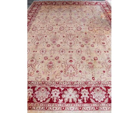 A cream ground Persian type carpet with main red border, centre with repeating foliate forms, 450 x 368 cms.     