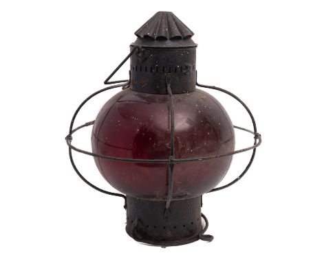 A wrought iron ship's lantern of circular form with red glass shade, 39cm high, 34cm diameter. 