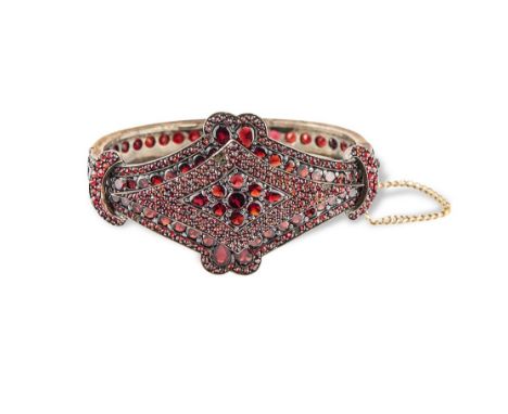 Antique silver bangle set with garnets.Ratchet clasp with safety chain.Internal dimensions : 5.5 x 4.5 cmGross weight : 26.2 