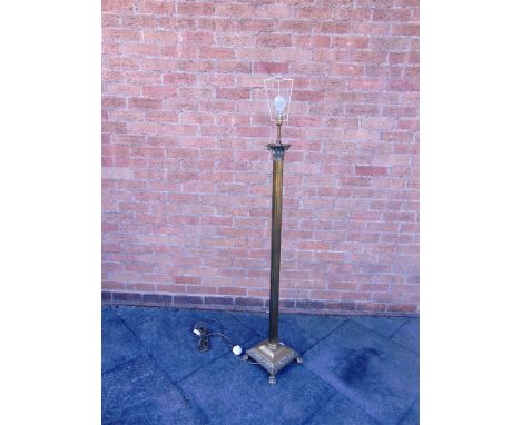 A BRASS CORINTHIAN COLUMN FLOOR LAMP the square base raised on four lions paw feet and with fringed shade, 175cm high inc. sh
