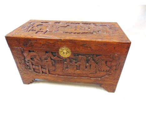 A CARVED CAMPHORWOOD TRUNK,  allover carving of figures in sailing craft etc., 100cm wide 50cm high 59cm deep