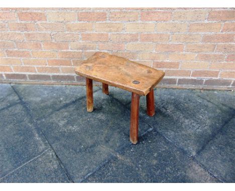 A RUSTIC FRUITWOOD STOOL  on four tapering supports, the top 52cm wide 29cm deep