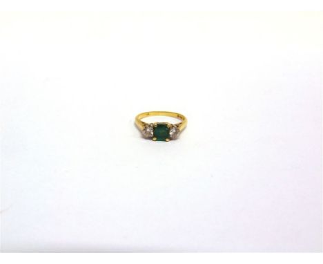 AN EMERALD AND DIAMOND THREE STONE 18 CARAT GOLD RING the square cut stone flanked by brilliants of approximately 0.3 carats 