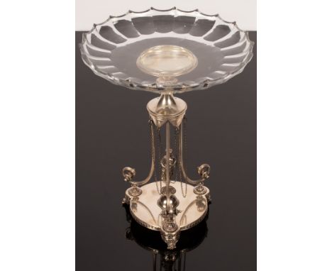 A silver plated table centrepiece, the glass platter supported on reeded scroll supports to a platform base with central figu