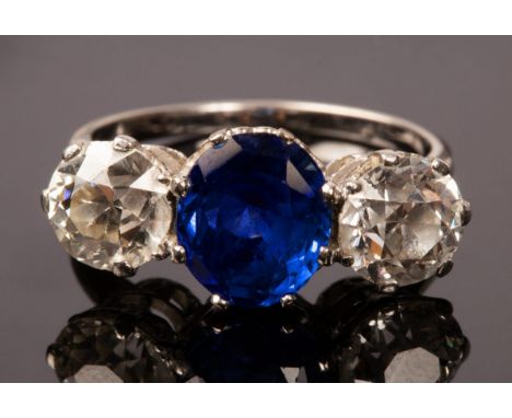 A sapphire and diamond three-stone ring, the central sapphire of slight cushion-shape flanked by diamonds with galleried sett