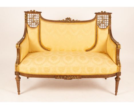 A 19th Century giltwood two-seater sofa with carved cresting and pierced trellises to the sides, having scroll arms on spiral