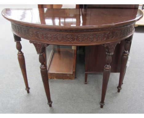 An 18th century style demi-lune console table with carved frieze on four turned supports, 124cm wide. 