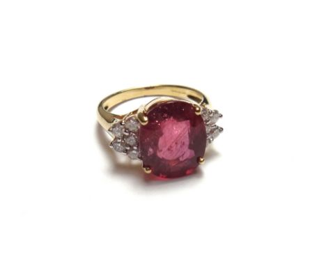 An 18ct gold, ruby and diamond set ring, claw set with the oval cut ruby at the centre, between circular cut diamond set five