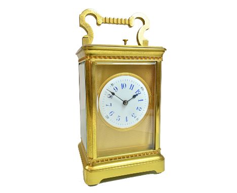 An Edwardian gilt brass cased carriage clock, with hour push repeat over a white enamel dial with bevelled glass panels and t