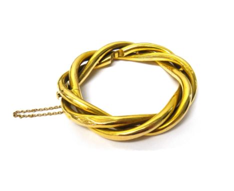 A gold oval hinged bangle, in a three row interwoven tubular design, on a snap clasp, fitted with a safety chain, gross weigh