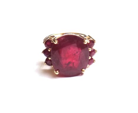 An 18ct gold and ruby set ring, claw set with the principal oval cut ruby at the centre, between circular cut ruby set three 