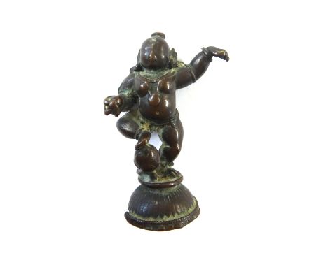 An Indian bronze  figure of bala Krishna, probably 17th century, standing in dancing pose, holding a butter ball in one hand,